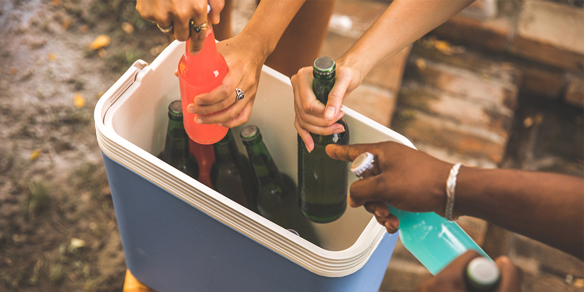 People getting drinks out of a cooler.